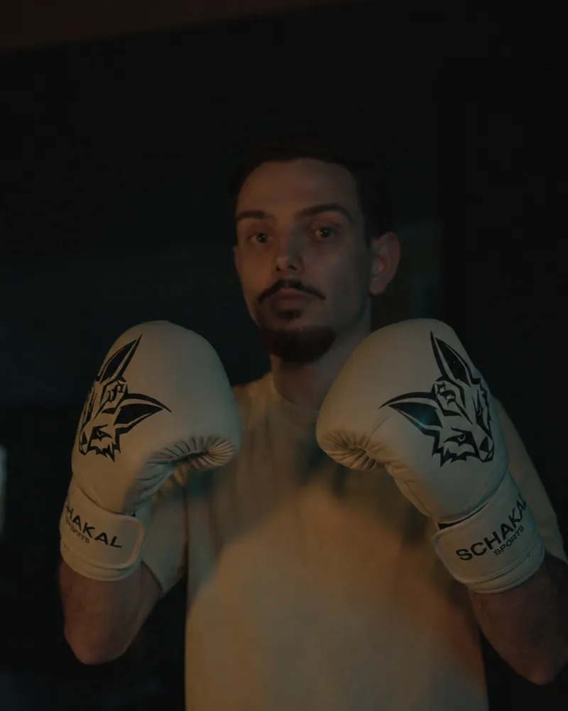 Athlet in Auslage mit weißen Schakal-Boxhandschuhen